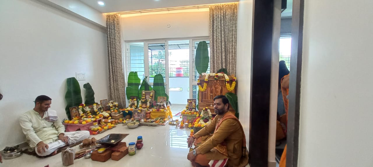 Acharya Ji and pandits seated before a decorated family altar